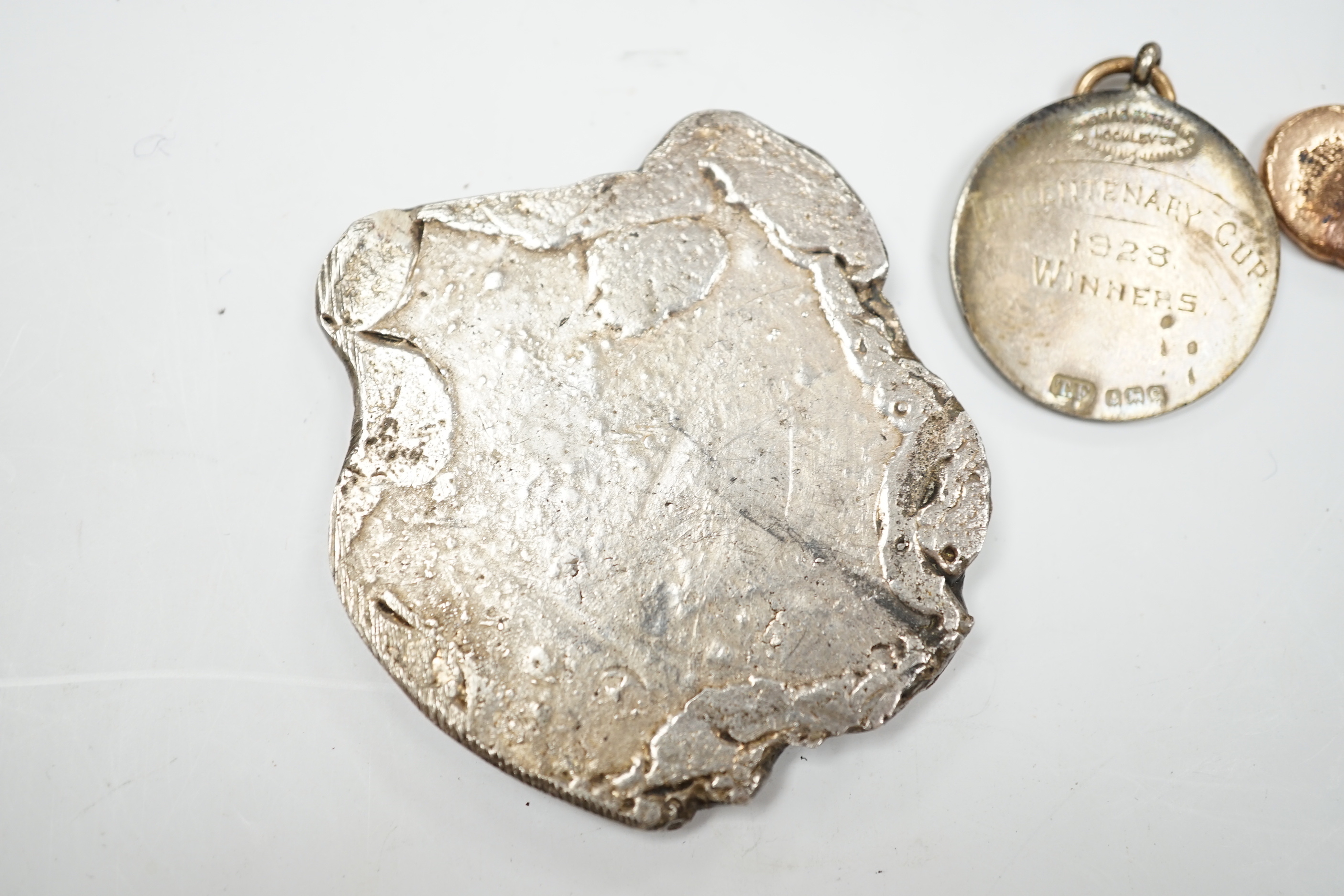 A silver charm bracelet, hung with assorted mainly white metal charms including tankard and Knight's helmet, two 'melted' ingots and a silver medallion.